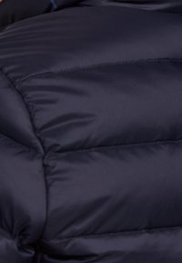 Granatowa kurtka puchowa o pikowanej fakturze, z gładką powierzchnią, grubą izolacją i subtelnymi detalami w szwie.