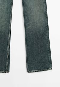 Jean en denim bleu coupe droite montré de la mi-cuisse à l'ourlet sur un fond blanc, mettant en valeur la texture du tissu et les détails des coutures.