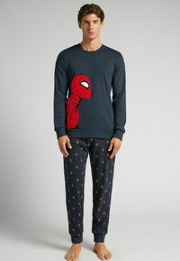 Camiseta de manga larga en color navy con un gráfico rojo de Spider-Man; pantalones de pijama a juego con motivos de araña rojos sobre un fondo navy; material de algodón.
