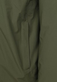 Olijfgroen jack met een gladde, matte textuur en een zijzak. Het ontwerp heeft minimalistische lijnen en verborgen stiksels.