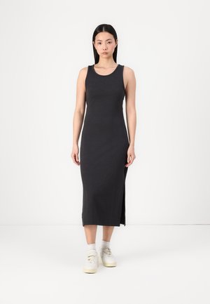 Sleeveless charcoal grey maxi dress with a fitted silhouette, side slit, and soft texture. Paired with white sneakers and ankle socks.