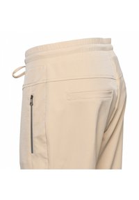 Beige broek met een elastische tailleband, gestructureerde stof, een zijrits zak en een platte achterzak, met een gladde, op maat gemaakte lijn.