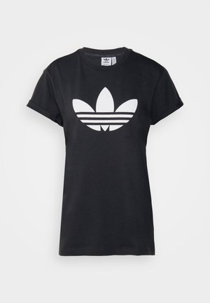 Musta puuvillainen t-paita, jossa on käärityt lyhyet hihat ja suuri valkoinen Adidas Trefoil -logo, jonka alla on kolme vaakasuoraa raitaa.