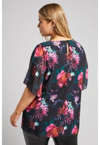 Blusa floreale in chiffon nero con fiori rosa, viola e turchesi. Presenta maniche corte e una schiena a occhiello con chiusura a bottone.