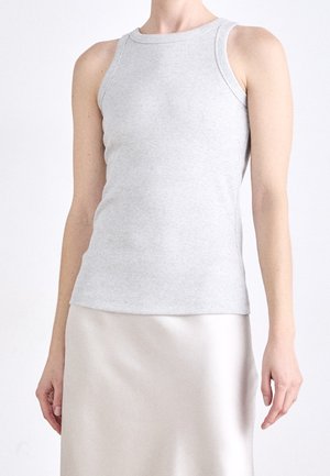 Person wearing a fitted light gray ribbed tank top and a smooth, light-colored satin skirt against a plain background.