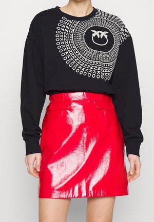 Sort sweatshirt med hvid grafisk print på den ene side og skinnende rød miniskirt med høj talje og flade frontlommer.