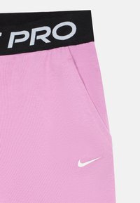 Lyserøde atletikshorts lavet af glat stof, med et sort elastisk taljebånd med "PRO" tekst og en lille hvid Nike-logo accent.