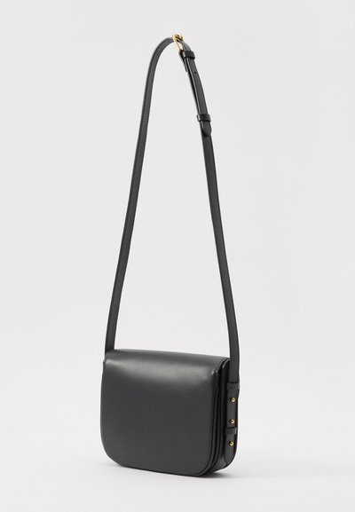 Black leather crossbody bag with a rectangular shape, adjustable strap, and gold hardware accents on the side. Smooth texture, minimal design.