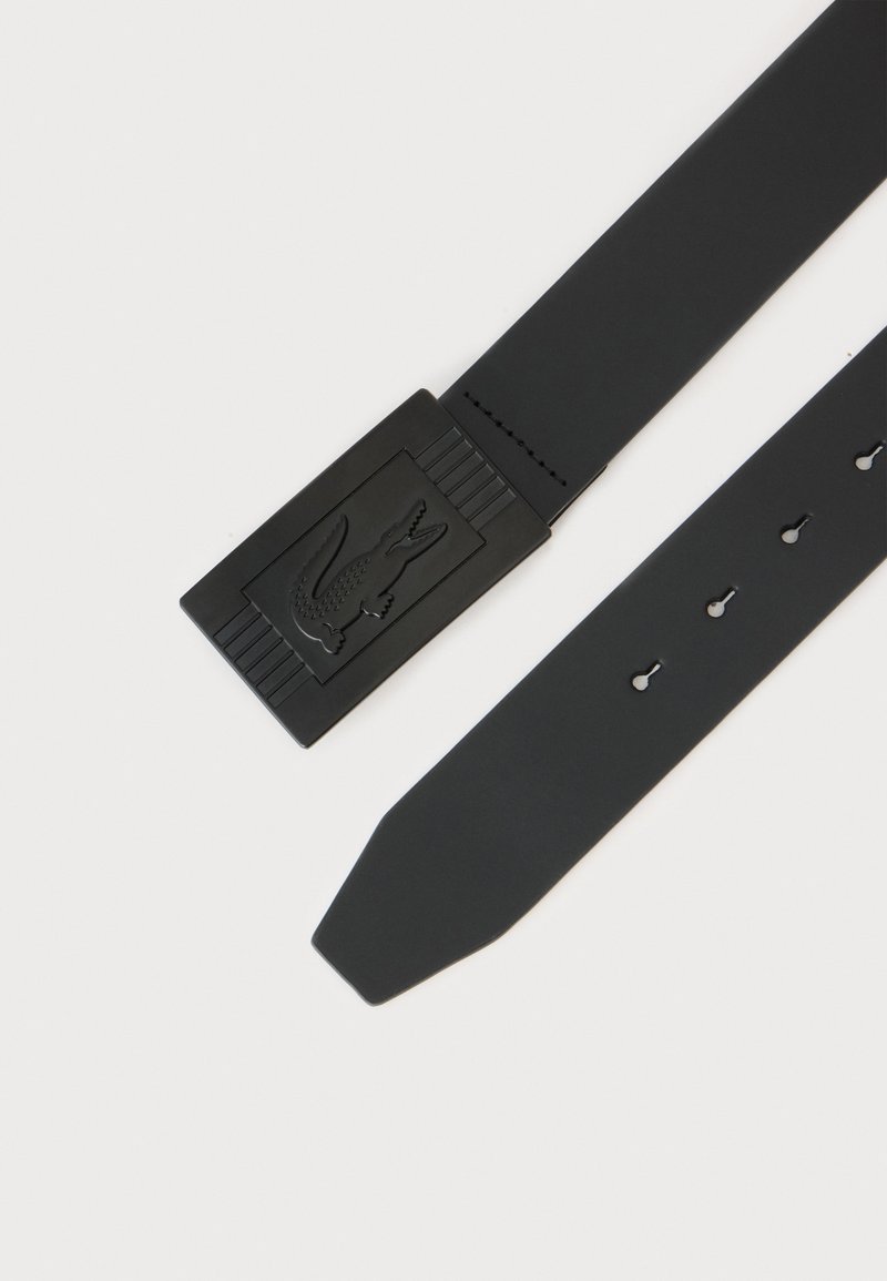 Black belt with rectangular buckle featuring embossed crocodile logo and multiple adjustment holes on the strap.
