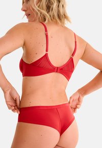 Ensemble de lingerie rouge comprenant un soutien-gorge en tulle transparent avec des bretelles réglables et une bande simple, assorti de culottes hipster lisses.