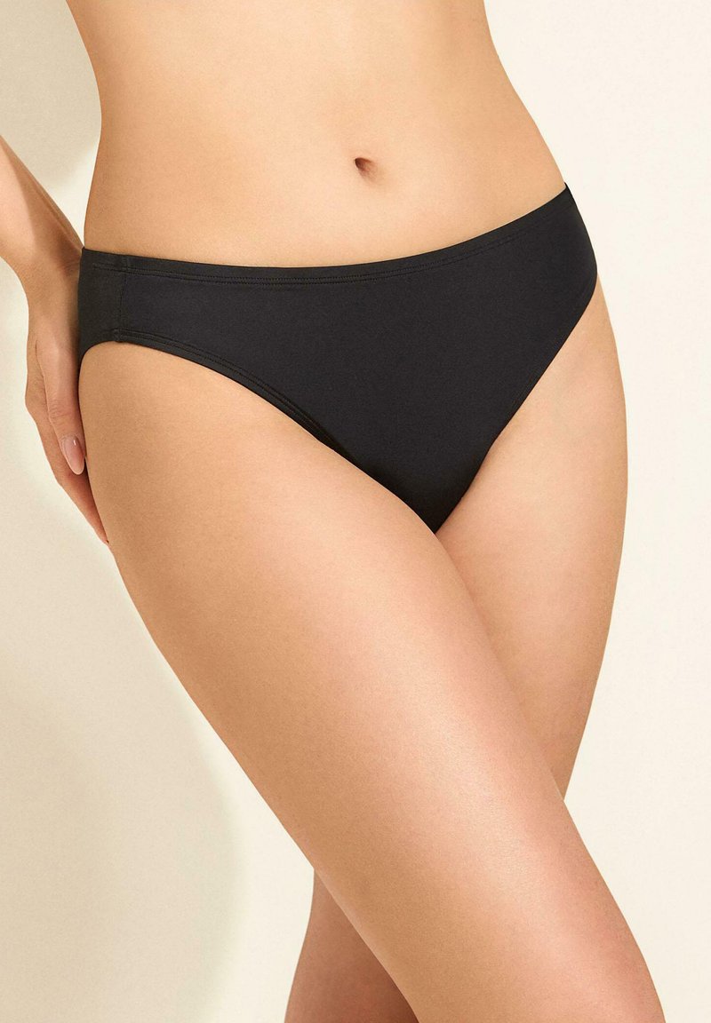 Czarny dół bikini o gładkiej fakturze, niskim stanie i minimalnych szwach, z klasycznym krojem zapewniającym komfort i dopasowanie.