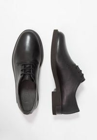 Scarpe stringate in pelle nera con finitura liscia, punta arrotondata e tacco in gomma basso; logo inciso sulla soletta.