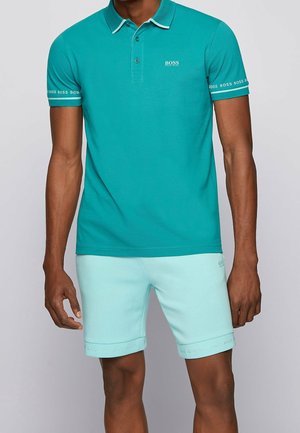 Turkusowa koszulka polo z kołnierzykiem i zapięciem na dwa guziki, zestawiona z jasnoniebieskimi szortami z akcentami logo na mankietach.