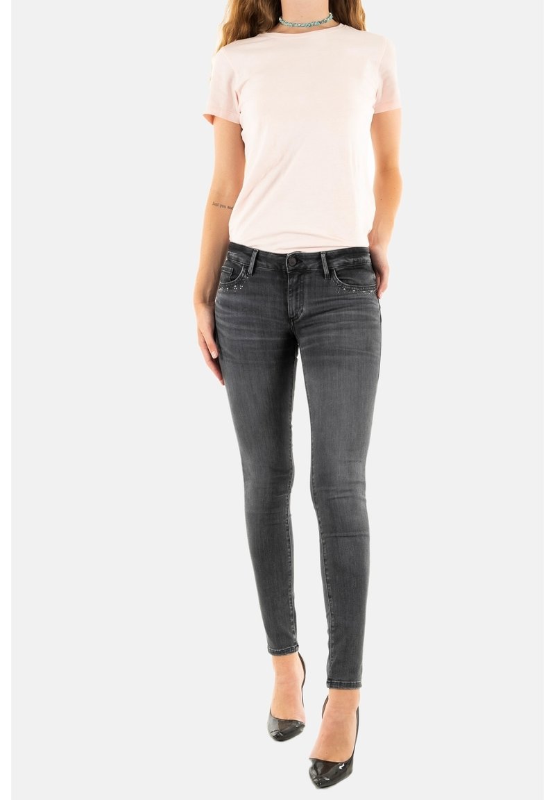 Ljusrosa t-shirt, slim fit, kortärmad. Mörkgrå skinny jeans med fem fickor och dekorationer. Svarta klackskor fullbordar outfiten.
