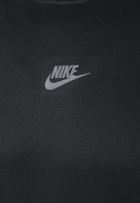 Svart idrottströja gjord av texturerat tyg med en liten grå Nike-logotyp på bröstet, rund halsringning och korta ärmar.
