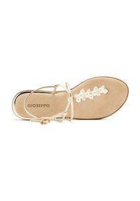 Sandale beige clair avec une semelle plate, présentant de fines lanières, un accent floral blanc décoratif et un subtil contour métallique autour du bord.