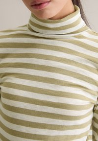 Golf z miękkiego materiału z naprzemiennymi poziomymi paskami w kolorze oliwkowozielonym i białym. Dopasowany krój o gładkiej fakturze.