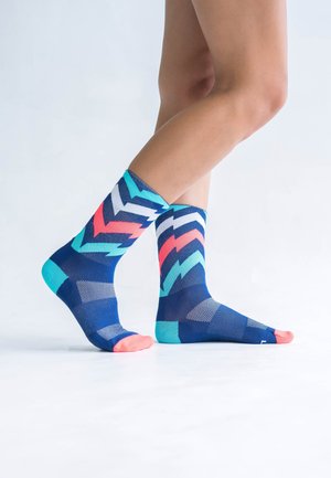 Colorful socks with a blue, pink, and teal zigzag pattern, knit fabric, ankle-length, with light pink and teal accents on the toe and heel.