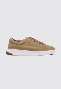 Zapatillas de ante marrón con cordones marrones, media suela blanca y suela de goma de contraste. Presenta una textura suave y un diseño minimalista.