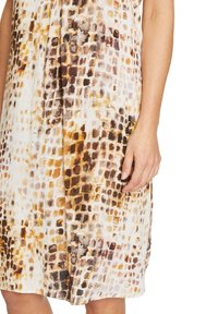 Sleevitön mekko, jossa on abstrakti vaaleanruskea ja kermaisuuden kuvio, valmistettu pehmeästä, kevyestä kankaasta. Mekossa on löysä istuvuus ja roikkuva muotoilu.