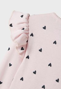 Lichtroze top met zwarte hartafdrukken, met een ontwerp van rimpelige mouwen. Soepele textuur met een zachte afwerking, elegante stikdetails.