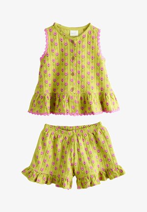 Ensemble composé d'un haut sans manches jaune-vert et d'un short avec un motif floral rose et des bords à volants, avec des boutons à l'avant du haut.
