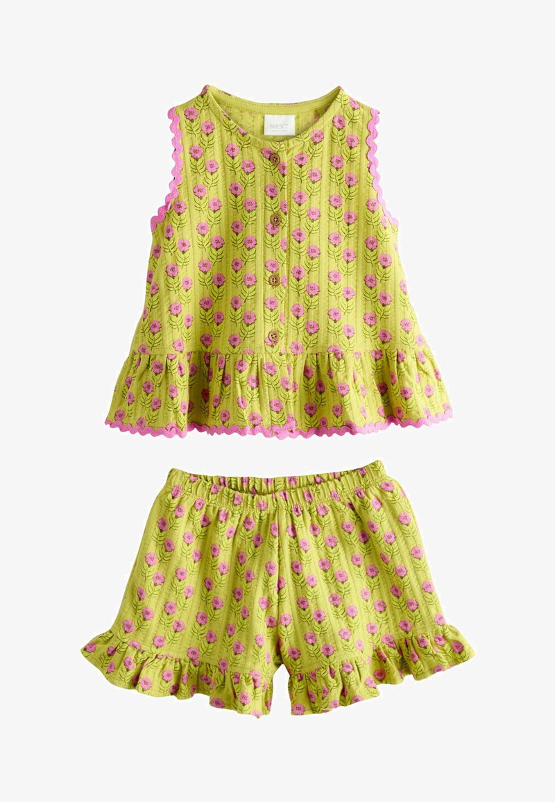 Ensemble composé d'un haut sans manches jaune-vert et d'un short avec un motif floral rose et des bords à volants, avec des boutons à l'avant du haut.