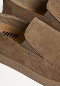 Barna velúr slip-on cipők elasztikus oldalpanellel, textúrált felülettel és parafa talpbetéttel. A felső részen kontrasztos varrás található.