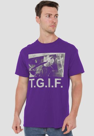 Mann trägt ein lila T-Shirt mit einem Bild einer maskierten Figur, die eine Machete hält, und dem Text „T.G.I.F.“ vorne.