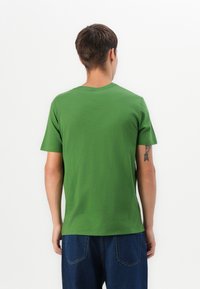 Green cotton t-shirt with short sleeves, round neckline, and a smooth texture. Features a plain design with no visible patterns or accents.