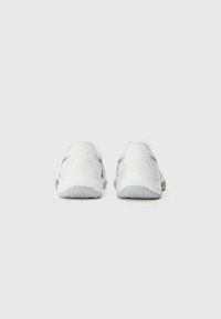Baskets de sport blanches avec une tige synthétique lisse, des accents gris, une semelle rembourrée et une semelle extérieure en caoutchouc texturé. Vue arrière montrant les détails de conception.