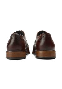 Dark brown leather shoes with brogue detailing, round toe, and a wooden heel. Textured finish and contrasting stitching visible.