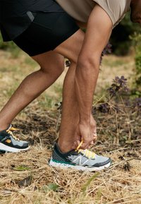 Gray and black running shoes with yellow laces, featuring a textured upper and a cushioned sole, styled for outdoor use.
