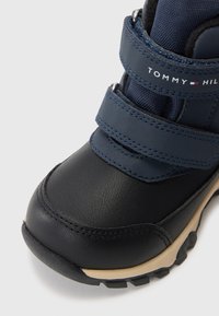 Μαύρη και ναυτική μπότες με δύο βέλκρο ιμάντες, επάνω από δερμάτινη υφή, καουτσούκ σόλα και αντίθετους μπεζ τόνους στη σόλα.