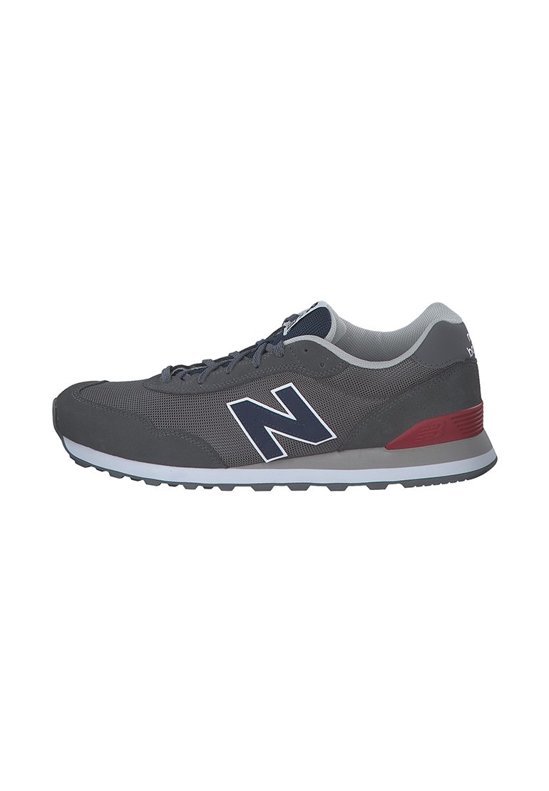 Grauer Sportschuh aus Mesh- und Wildledermaterialien, mit einer weißen Zwischensohle, roten Akzenten und einem auffälligen navyblauen 'N'-Logo.