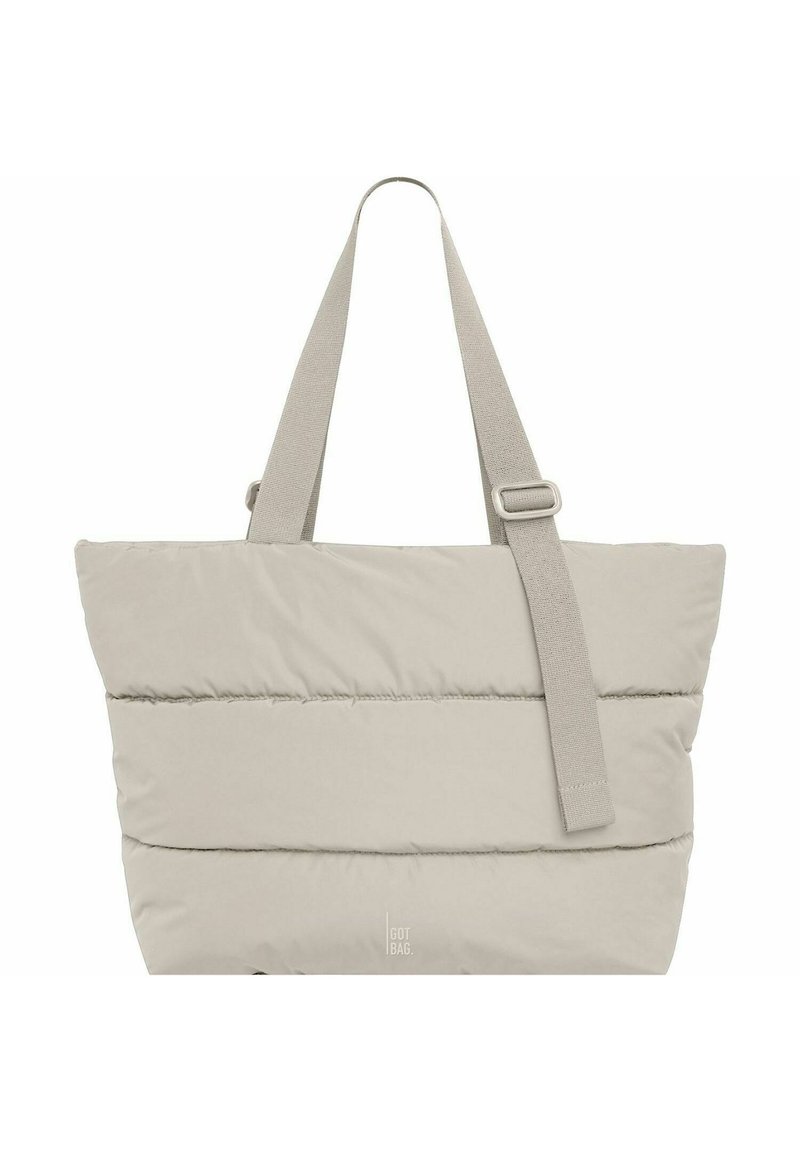 Beige totebag van luchtig materiaal met brede banden en verstelbare hardware; heeft horizontale stiksels en een zachte textuur.