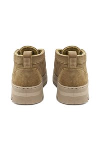Botas de tobillo de ante marrón con un acabado texturizado, que presentan un cuello acolchado y suela de goma. Incluyen una tira trasera para facilitar el calzado.