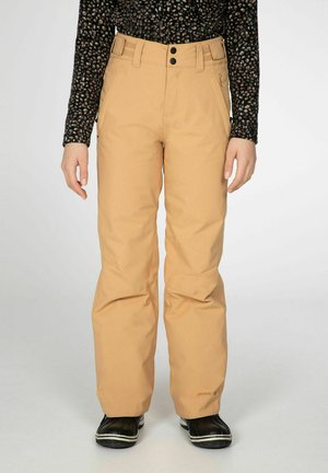 Pantalons de neige beige avec une coupe droite, deux poches avant, double bouton et des bandes élastiques à la taille, associés à des bottes noires imperméables.