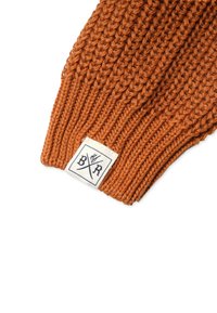 Orangene Strickmütze mit gerippter Textur. Verfügt über ein weißes Etikett mit schwarzer Schrift und einem Kreuzdesign nahe dem Rand.