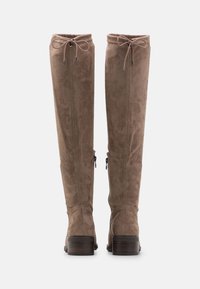 Botas marrones de ante por encima de la rodilla con un tacón de madera ligeramente elevado, cierres con cremallera lateral y cordón ajustable en la parte superior.