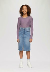 Langdurige paarse top met een geribbeld patroon, gecombineerd met een lichtblauwe denim kokerrok met een split aan de voorkant, en witte sneakers.