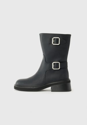 Black leather ankle boots with two silver buckles, a rounded toe, and a chunky heel. The texture is smooth with a slight sheen.