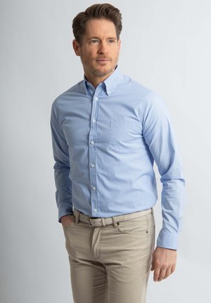 Lichtblauw overhemd met knopen en een klein ruitpatroon, met een borstzak en lange mouwen, gecombineerd met beige broek en een riem.