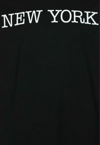 T-shirt noir avec un texte en gras blanc "NEW YORK" en majuscules, centré en haut, dotée d'une texture de tissu lisse.