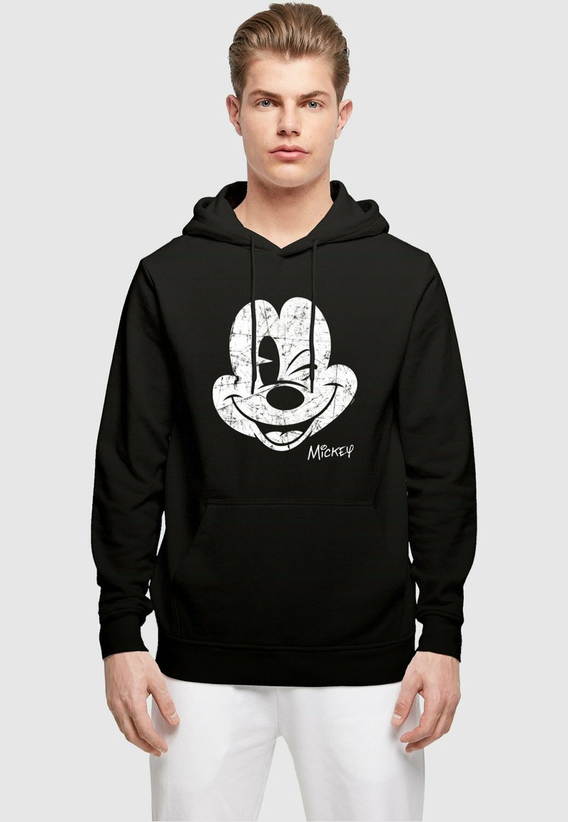 Fekete kapuccsinos pulóver, melyen egy nagy, fehér, megkopott Mickey Mouse grafika található az elején. Elülső zsebbel és húzózsinórral ellátott kapucnival rendelkezik.