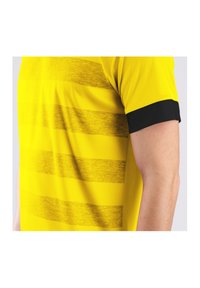 Gelbes Sporttrikot mit horizontalen strukturierten Streifen, schwarzen Ärmeln und einem eleganten Design, hergestellt aus leichtem, atmungsaktivem Material.