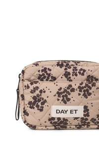 Gepolstertes Kosmetiktäschchen in Beige mit dunklem Blumenmuster. Es hat eine rechteckige Form und einen Reißverschluss. Das Etikett trägt die Aufschrift "DAY ET."