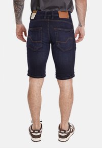 Shorts in denim blu scuro con vestibilità slim, caratterizzati da due tasche posteriori, dettagli cuciti e un'etichetta in pelle sulla vita.