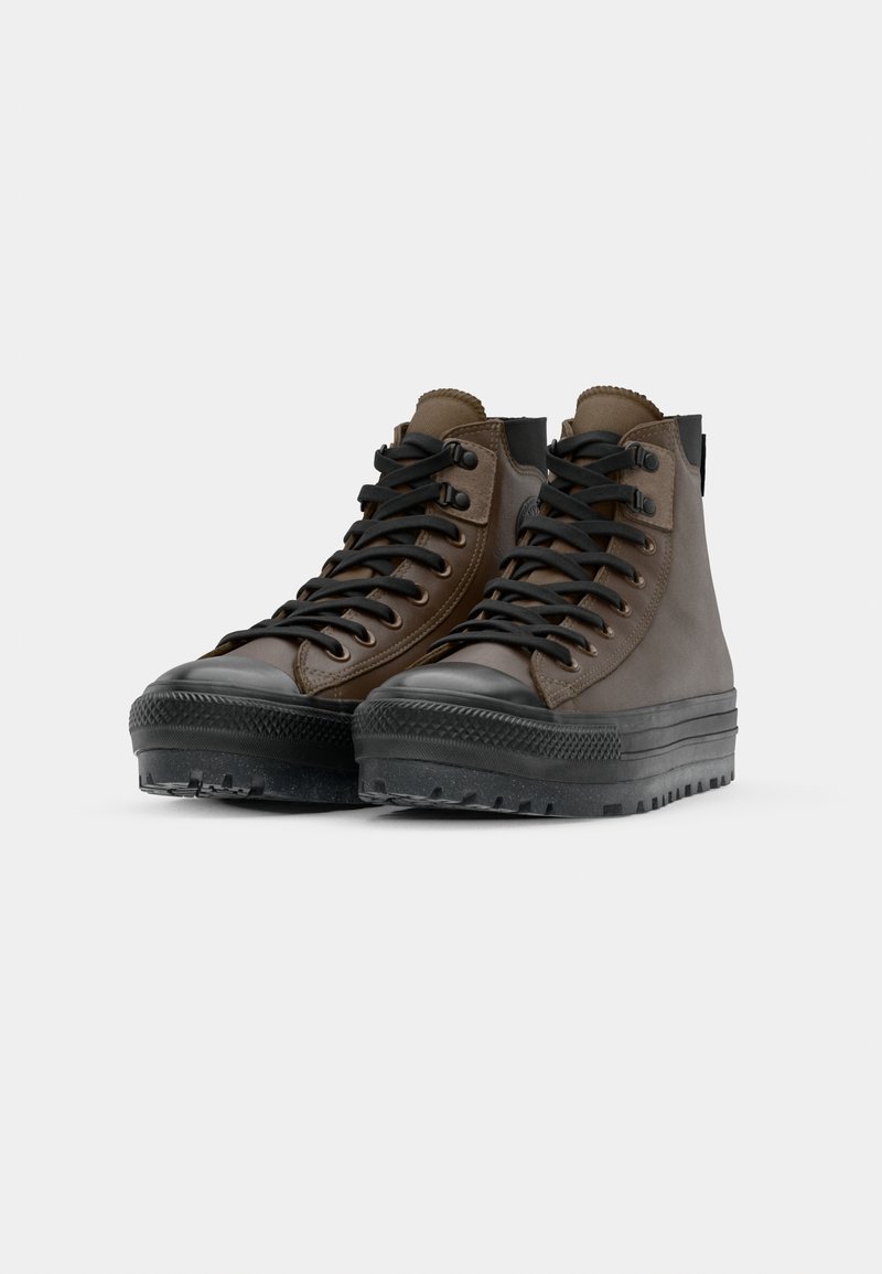 Scarpe alte in pelle marrone con suole in gomma nera, dotate di lacci rotondi, occhielli in metallo e una finitura testurizzata.