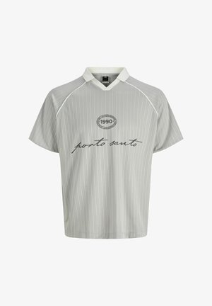 Bly blond dreng står vendt mod højre iført gråstribet "porto santo" skjorte, sorte vidde bukser og sorte sneakers på hvid baggrund.